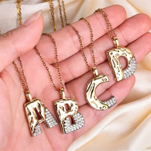 Detail of A B C D letter pendants with lava texture and zircons on gold chains