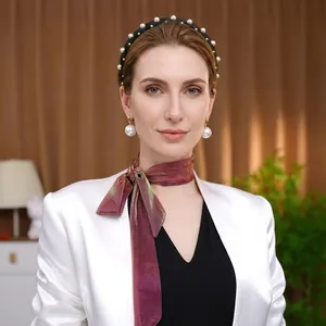Detail of silk-like gradient chiffon shawl with elegant pearl accessories and white blazer