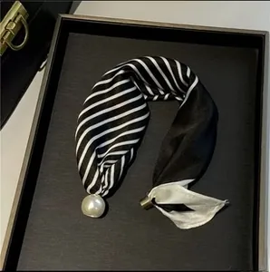 Detail of black and white striped scarf with large white pearl and gold metal ring