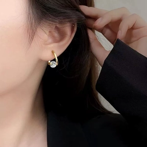 Élégantes boucles d'oreilles dorées avec zircon flottant portées par un mannequin