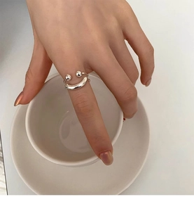 Macro shot of minimalist S925 silver double-layer smiley face open ring on a finger