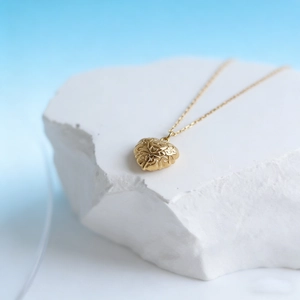 Close-up of vintage heart pendant with embossed floral patterns on white stone