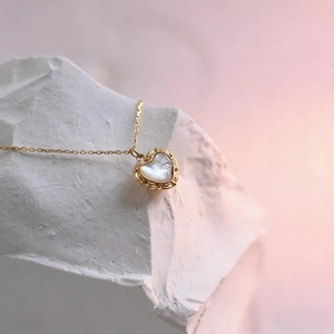 Detailed macro view of heart shell pendant with vintage gold floral edges and fine chain