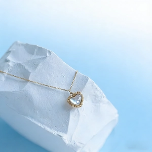 Detail of vintage heart pendant with iridescent shell inlay on thin gold chain
