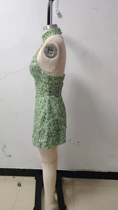 Detail of green sequin dress showing shimmering material and high-neck sleeveless design