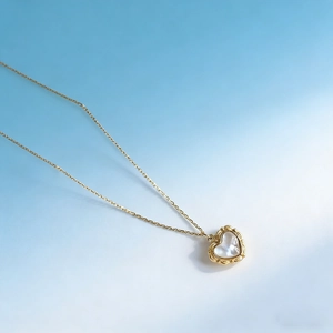 Macro shot of gold heart necklace pendant with white mother of pearl inlay and floral pattern