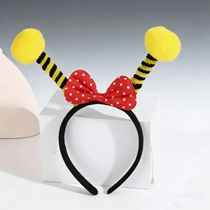 Detail of bee headband with a red polka dot bow and yellow fuzzy pom-pom antennae