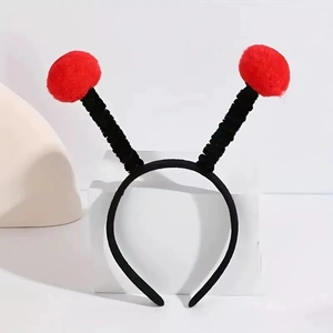 Detail of bug-themed headband with red fuzzy pom-poms and black fabric-wrapped frame