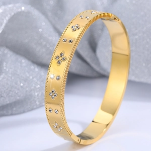 Detail of gold brushed titanium bracelet with four-leaf clover patterns and small rhinestones