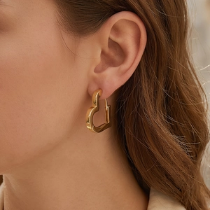 Minimalist hollow heart hoop earrings in gold finish worn by model on ear