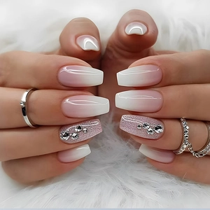 Close-up of French ombre press-on nails with glitter accents and 3D rhinestone details