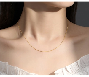 Close-up of a delicate gold box chain necklace on model neck for a minimalist jewelry look