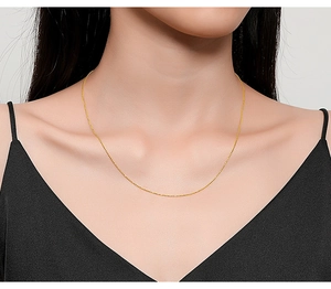 Close-up of minimalist gold beaded chain necklace on skin with elegant thin link detail