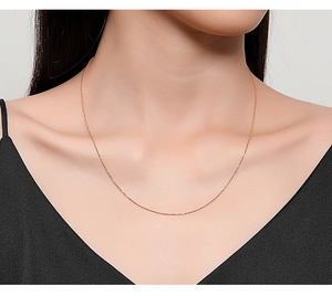 Close-up of minimalist rose gold beaded chain necklace on model neck showing fine detail