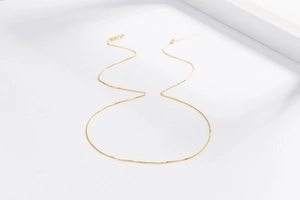 Detail of 18K gold-plated box chain with needle pin and spring clasp on white background