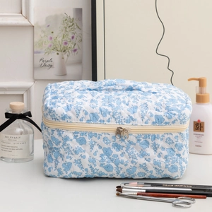 Détail d'une trousse à maquillage matelassée fleurie avec poignée et double fermeture
