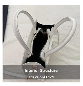 Detail view of the white leather handbag showing black interior lining and metal zipper