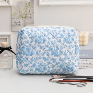 Détail d'une trousse de maquillage matelassée en coton avec motif floral bleu et fermeture
