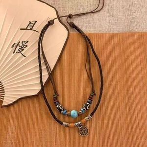 Detail of vintage double-layer necklace with wooden beads and antique copper coin pendant