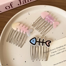 Detail von drei fischgrätenförmigen Acetathaarnadeln und Clips auf einem weißen Tablett