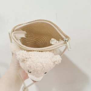 Vue détaillée du sac bandoulière en paille pour enfant avec ours en peluche et zip