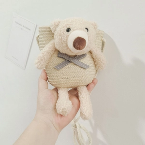 Détail d'un sac bandoulière en paille avec ours en peluche et bandoulière corde