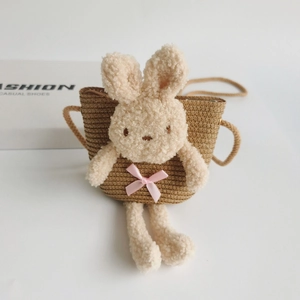 Détail du sac en paille pour enfants avec un lapin en peluche et un nœud en satin rose