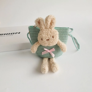 Détail d'un sac en paille vert menthe avec une poupée lapin en peluche 3D et un nœud