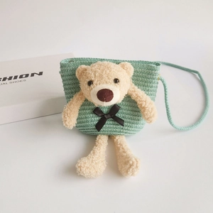 Detail of mint green straw crossbody bag featuring a plush bear and fine woven texture