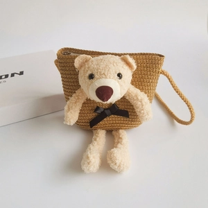 Detail of straw woven mini bag featuring a plush teddy bear and secure metal zipper