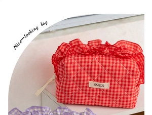 Detail of red checkered quilted cosmetic bag with ruffled edges and fabric label