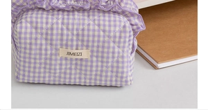 Close-up of lavender plaid quilted makeup bag with ruffle trim and JIMEIZI logo label