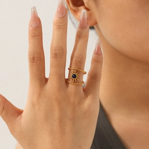 Detail of double-layer gold sunburst ring with blue stone inlay worn by a model