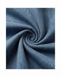Macro view of blue denim fabric texture showing soft twill weave and spiral folds