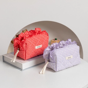 Detail of ruffled lace trim and quilted plaid patterns on purple and red cosmetic bags