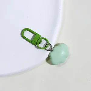 Macro detail of a bright green cloud-shaped resin pendant with a metal alloy keychain