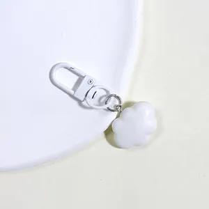 Close-up of white minimalist resin cloud keychain with matte finish and matching lobster clasp