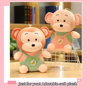 Detail of cute orange and pink plush monkeys wearing banana pattern overalls on a desk