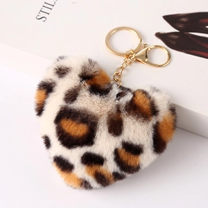 Detail shot of a fluffy leopard print heart-shaped keychain with gold metal ring on a magazine