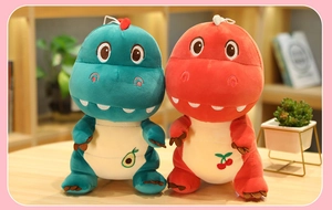 Detail of plush dinosaur toys in teal and orange with embroidered avocado and cherry fruit