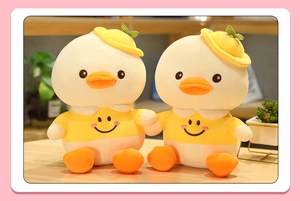 Close-up of cute yellow plush duck couple dolls with embroidered smiley face shirts
