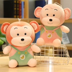 Pair of 40cm plush monkeys with colorful overalls and banana embroidery on wooden table