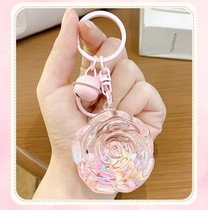Close-up of translucent pink rose resin keychain with colorful stones and small bell charm