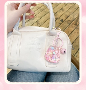 Pink bottle liquid glitter keychain with bell and lobster clasp on a stylish handbag