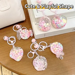 Cute pink candy bean acrylic keychains with strawberry and bear charms on wood surface