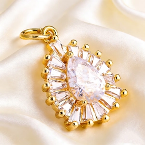 Macro shot of gold-plated teardrop pendant with white cubic zirconia on silk background