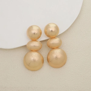 Detail of gold triple-tiered round earrings with elegant matte brushed metal texture
