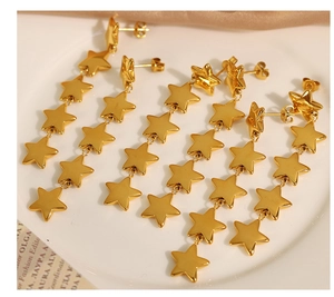 Gros plan de boucles d'oreilles étoiles dorées en acier sur une assiette en céramique