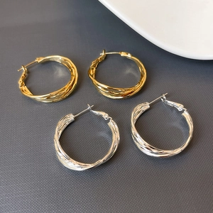 Minimalist silver and gold layered twist hoop earrings with spiral metal texture