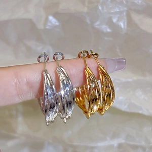 Close-up of gold and silver layered hoop earrings with twisted texture held by hand